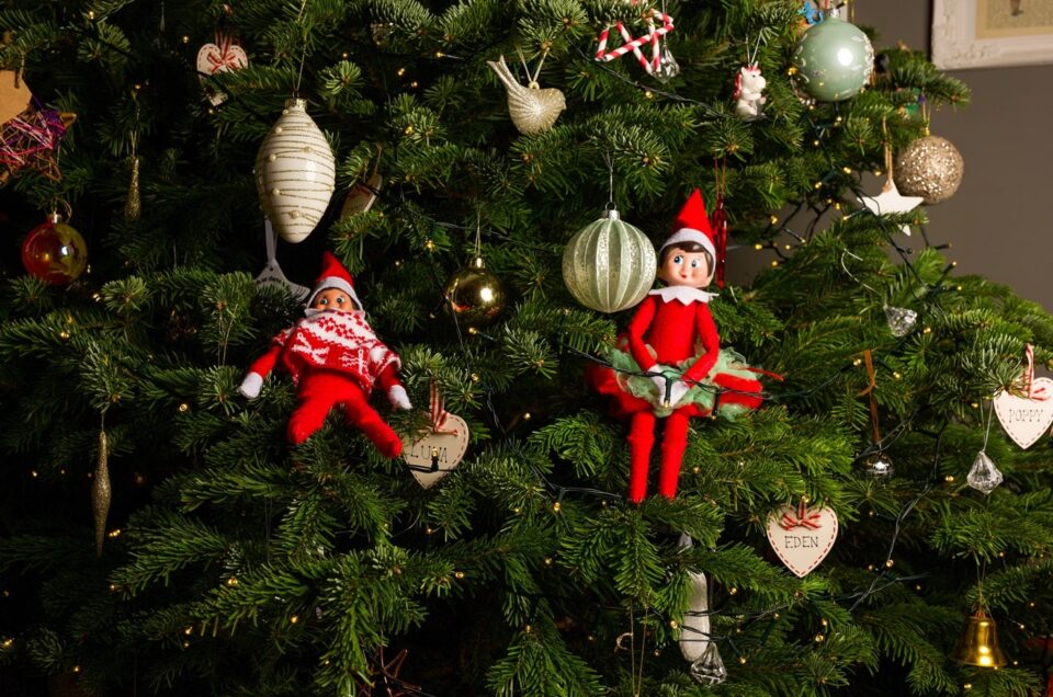 A Christmas tree with two Elfs sat within the tree.