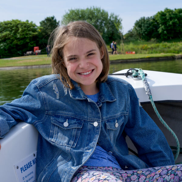 A girl smiling whilst sat on a boat.