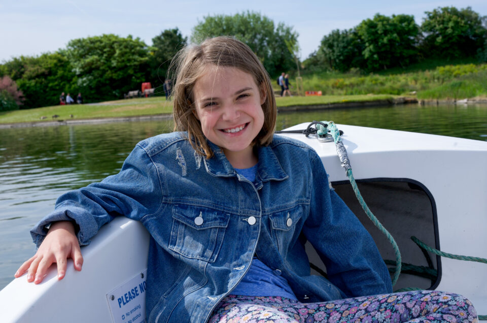 A girl smiling whilst sat on a boat.