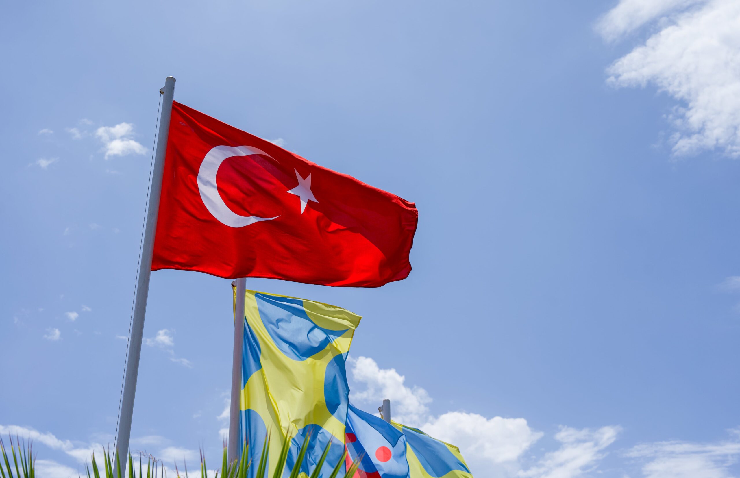 The Turkey flag flying on a blue sky background.
