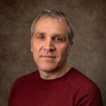 A portrait of a man in a red jumper.